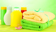 Baby cosmetics and towels on wooden table, on green background