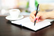 Foto: Hand signing in notebook, on bright background Hand signing in notebook, on bright background