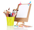 Photo: Small easel with sheet of paper with art supplies isolated Small easel with sheet of paper with art supplies isolated