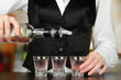 Barmen hand with bottle  pouring beverage into glasses,