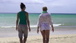 Two young girlfriends walking on the beach
