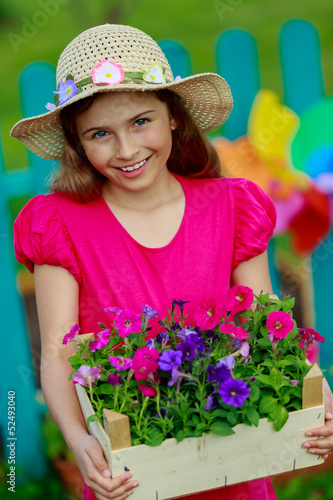 Photo: Gardening- lovely girl with petunia flowers in the garden Gardening- lovely girl with petunia flowers in the garden