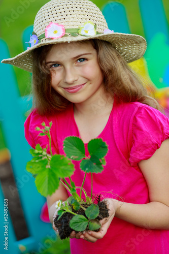 Photo: Gardening- lovely girl with strawberry seedling in the garden Gardening- lovely girl with strawberry seedling in the garden