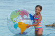 Photo: Lovely girl playing in the sea with inflatable globe ball. Lovely girl playing in the sea with inflatable globe ball.