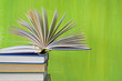 pile of books, one open,  green background, free copy space