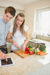 Couple looking at tablet pc while cooking