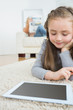 Girl using tablet with her mother reading the newspaper