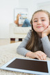 Happy girl with her tablet pc and her mother reading newspaper