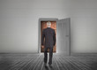 Businessman walking towards door open but blocked by red brick w