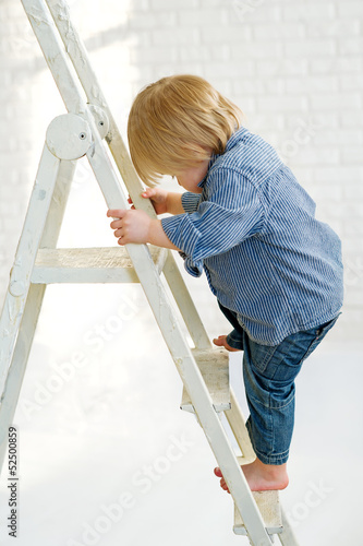 Photo: Little boy learning to climb the ladder Little boy learning to climb the ladder
