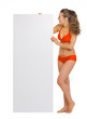 Happy young woman in swimsuit looking on blank billboard