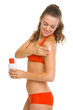 Happy young woman in swimsuit applying sun block creme