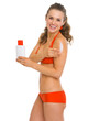 Smiling young woman in swimsuit applying sun screen creme