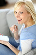 Cheerful girl using smartphone sitting in sofa