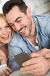 Cheerful couple having fun using smartphone