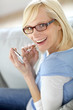 Foto: Cheerful girl using smartphone sitting in sofa Cheerful girl using smartphone sitting in sofa