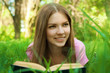 Close up portrait of smiling girl reading book at the park