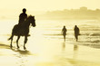Riders and her horse gallop along the beach