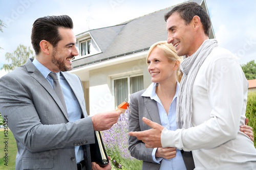 Photo: Salesman giving home keys to property owners Salesman giving home keys to property owners