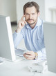 Photo: Businessman sitting in front of computer monitors Businessman sitting in front of computer monitors