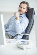 Photo: Handsome businessman sitting in chair in front of computer Handsome businessman sitting in chair in front of computer