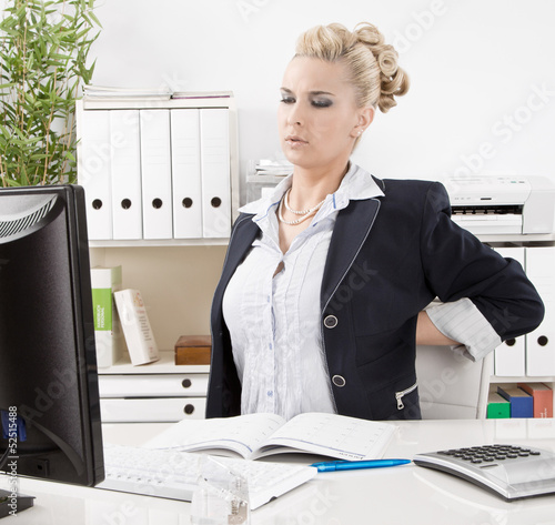 Photo: Frau hat Rückenschmerzen im Büro Frau hat Rückenschmerzen im Büro