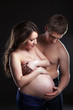 Young man caresses pregnant woman's belly