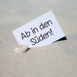 Muschel im Sand mit Karte AB IN DEN SÜDEN!