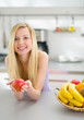 Portrait of happy teenager girl with apple in modern kitchen