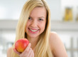 Portrait of smiling teenager girl with apple in kitchen