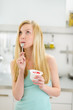 Thoughtful teenager girl eating yogurt in kitchen