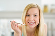 Smiling teenager girl with spoon of yogurt