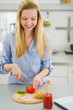 Happy teenager girl making sandwich in kitchen