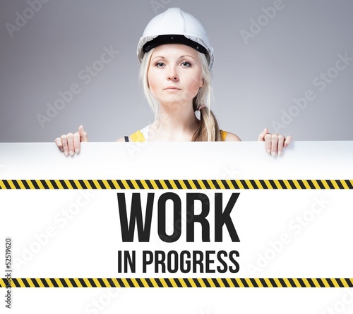 Photo: Worker holding work in progress sign on information board Worker holding work in progress sign on information board