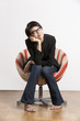 Thoughtful young Chinese girl sitting on chair