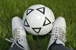 soccer ball between his legs against the grass