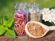 glass bottles with healing herbs on wooden board in sunset sunli