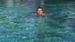Happy young man swimming in the pool, super slow motion