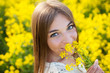 Cheerful girl smelling yellow wildflower
