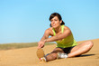 Athlete woman stretching leg on beach