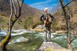 Young hiker woman standing on a stone near fast river in mountai