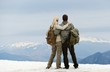 Couple of hikers with backpacks looking over mountains view