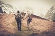 Couple of hikers with backpacks walking in the mountains