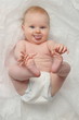 Cute happy 7 month baby girl in diaper lying and playing