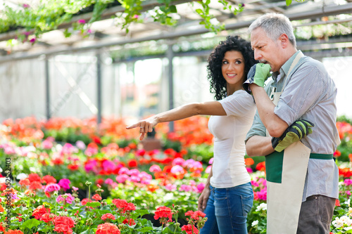 Photo: Female customer choosing flowers in a greenhouse Female customer choosing flowers in a greenhouse