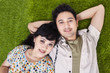 Asian couple laying on green grass