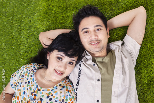Photo: Asian couple laying on green grass Asian couple laying on green grass