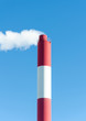 Industrial chimney with smoke over blue sky