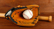 Baseball glove, bat and ball on wooden background
