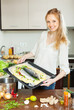 Smiling woman cooking fish in sheet pan